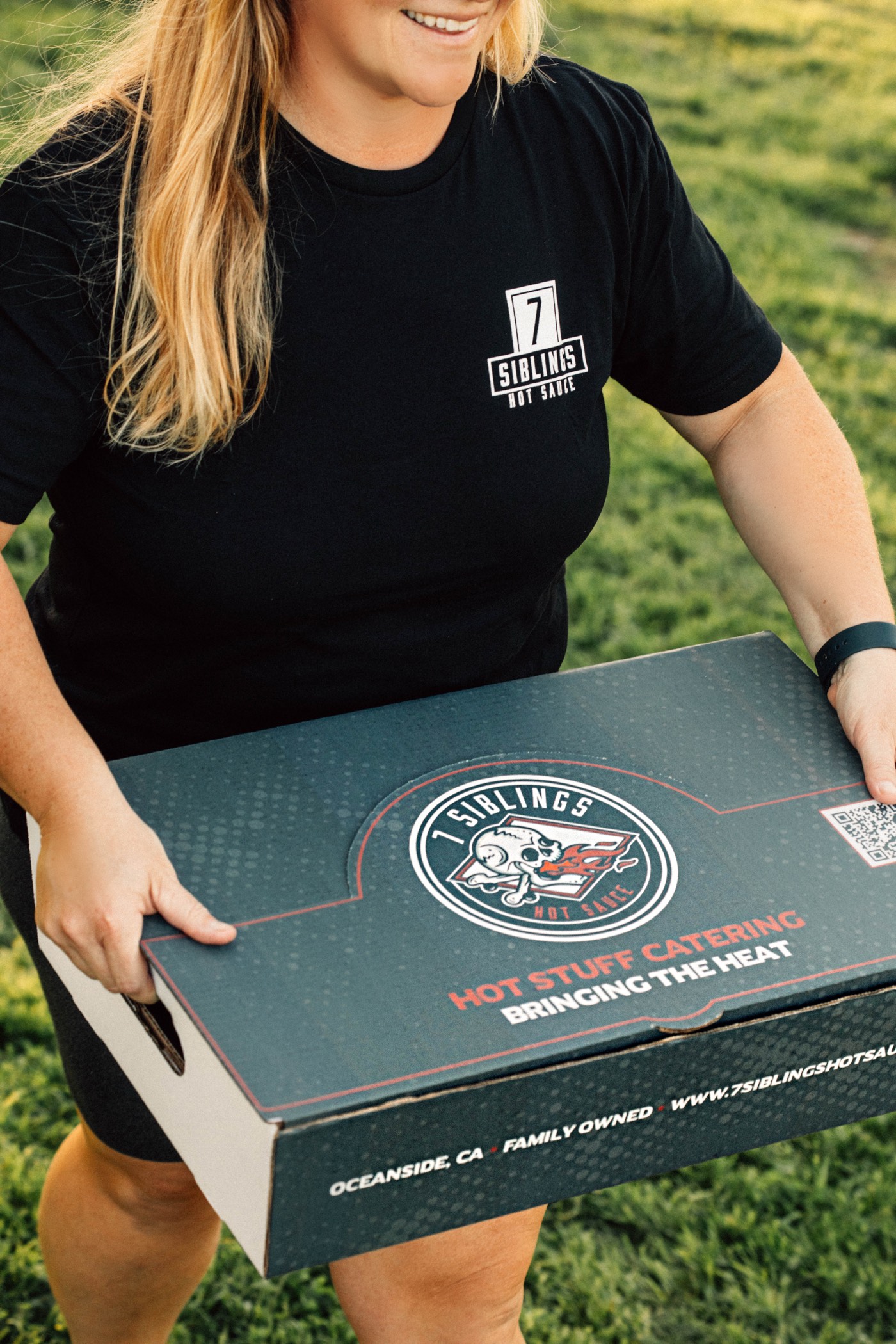 A 7 Siblings Hot Stuff Catering box being carried to an event