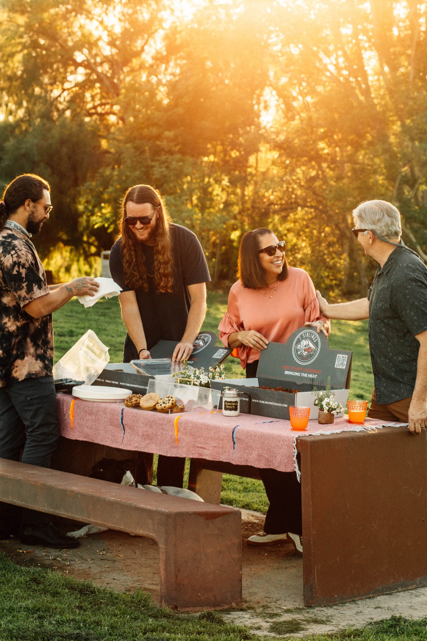 Guests serving themselves from 7 Siblings catering boxes at a picnic table